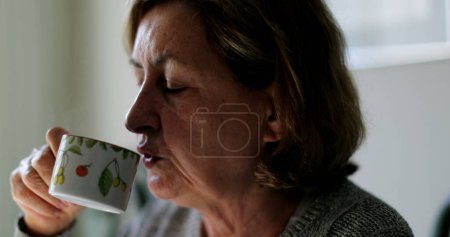 Foto de Mujer mayor cándida bebiendo café por la mañana - Imagen libre de derechos