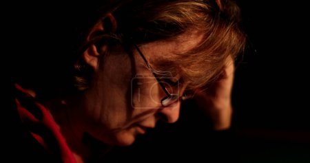Téléchargez les photos : Pensive femme âgée réfléchissant profondément dans l'obscurité personne âgée réfléchie - en image libre de droit