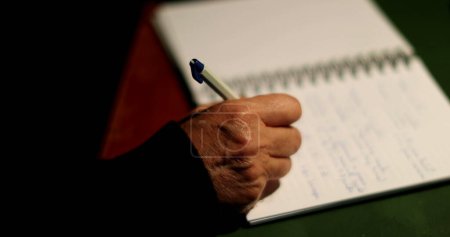 Téléchargez les photos : Personne âgée écrivant sur papier tenant stylo femme plus âgée écrit des notes la nuit - en image libre de droit