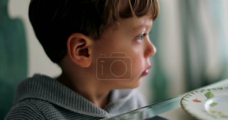 Foto de Pensativo niño triste mirando por la ventana - Imagen libre de derechos