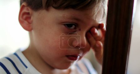 Téléchargez les photos : Un enfant fatigué frotte les yeux avec la main - en image libre de droit