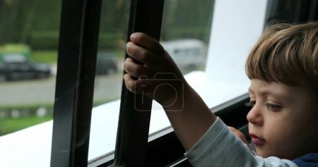 Foto de Bebé niño intenta abrir ventana niño tratando de deslizar ventana - Imagen libre de derechos
