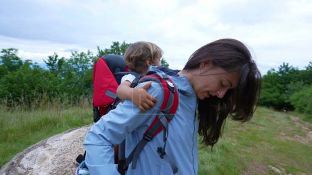Téléchargez les photos : Mère randonnée avec enfant portant son fils dans un porte-sac à dos à l'extérieur pendant le trekking - en image libre de droit