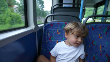 Téléchargez les photos : Enfant regardant par la fenêtre du bus voyageant par les transports publics - en image libre de droit