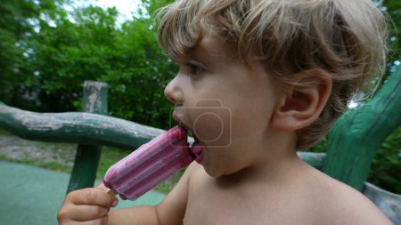 Foto de Niño comiendo helado afuera durante el día de verano - Imagen libre de derechos