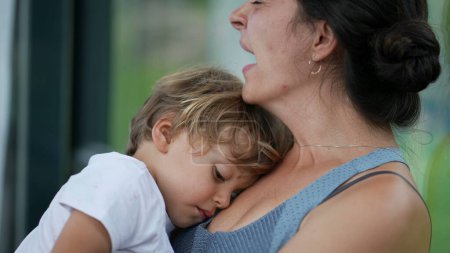 Téléchargez les photos : Mère fatiguée bâillant tenant l'enfant épuisé dans les bras parent somnolent et enfant - en image libre de droit