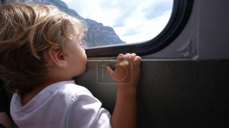 Téléchargez les photos : Enfant à l'intérieur du transport téléferique regardant par la fenêtre voyageant pendant les vacances - en image libre de droit