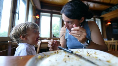 Téléchargez les photos : Mère nourrissant l'enfant au restaurant parent nourrit le déjeuner au petit garçon - en image libre de droit