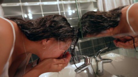 Téléchargez les photos : Femme lavage visage dans lavabo salle de bains - en image libre de droit