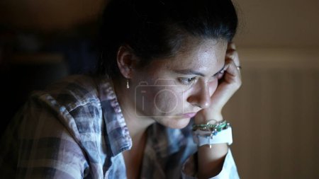 Photo for One woman in front of computer screen watching media late at night using laptop - Royalty Free Image