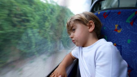 Foto de Un niño contemplativo viaja en autobús apoyado de cabeza en la ventana - Imagen libre de derechos
