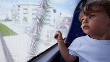 Téléchargez les photos : Enfant regardant par la fenêtre du bus pointant le passager de la ville enfant dans les transports publics - en image libre de droit