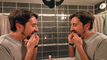 Téléchargez les photos : Homme appliquant lotion nettoyant lavage visage en face du miroir - en image libre de droit