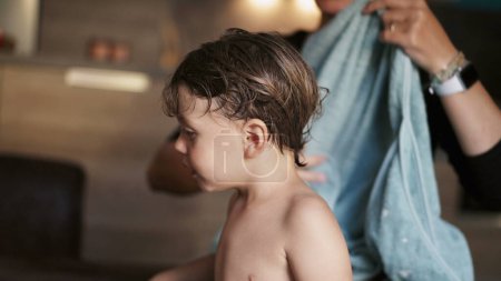 Téléchargez les photos : Mère séchant les cheveux de l'enfant avec serviette après le bain - en image libre de droit