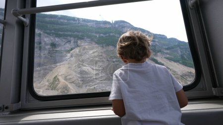Téléchargez les photos : Enfant à l'intérieur du transport téléphérique monter surplombant le paysage enfant pendant les vacances - en image libre de droit