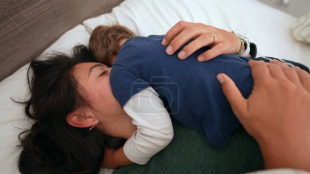 Téléchargez les photos : Parent et enfant embrasser dans le lit du matin - en image libre de droit