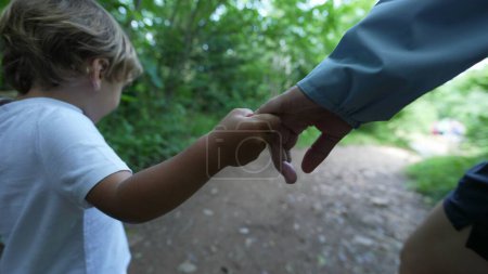 Photo for Parent and child holding hands hiking outdoors kid holds mother hand while trekking in nature - Royalty Free Image
