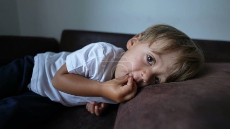 Foto de Niño comiendo cereal niño bocadillo acostado en el sofá - Imagen libre de derechos