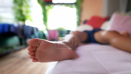 Téléchargez les photos : Enfant endormi sur le canapé gros pieds orteils couchés - en image libre de droit