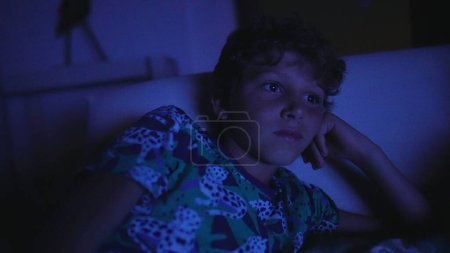 Téléchargez les photos : Enfant regardant un film à la maison la nuit - en image libre de droit