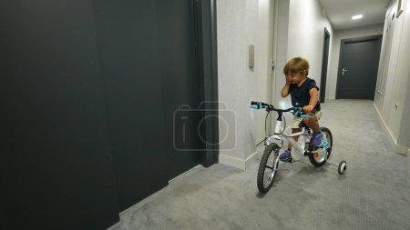 Téléchargez les photos : Enfant appuyant sur le bouton ascenseur entrant avec vélo - en image libre de droit