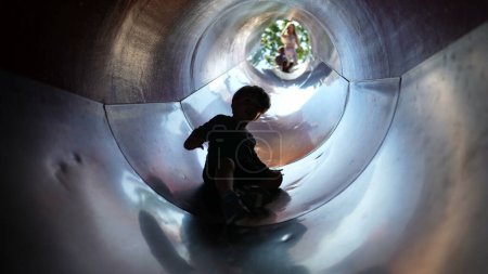 Téléchargez les photos : Silhouette de l'enfant à l'intérieur du tunnel coulissant à l'aire de jeux - en image libre de droit