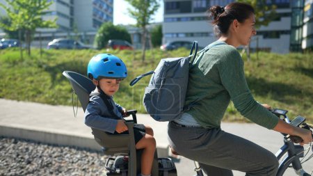 Photo for Mother riding bicycle with little boy sitting on back seat - Royalty Free Image