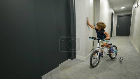 Foto de Niño pulsando el botón del ascensor entrando con bicicleta - Imagen libre de derechos