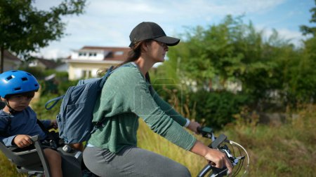 Foto de Ciclista madre paseos en bicicleta fuera en carretera verde con niño - Imagen libre de derechos