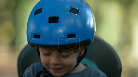 Foto de Niño con casco de bicicleta retrato niño sentado en el asiento trasero de la bicicleta - Imagen libre de derechos