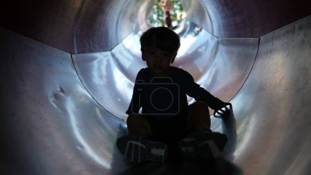 Téléchargez les photos : Silhouette de l'enfant à l'intérieur du tunnel coulissant à l'aire de jeux - en image libre de droit