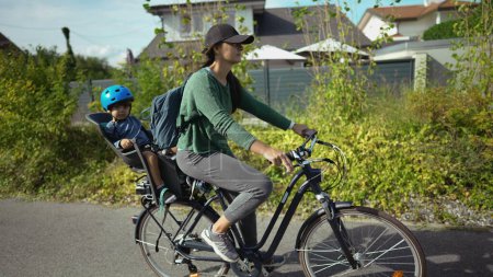 Téléchargez les photos : Femme vélo d'équitation avec tout-petit sur le siège arrière mère cycliste - en image libre de droit