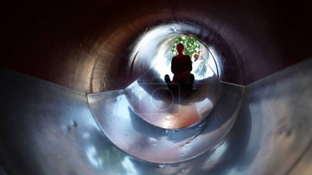 Téléchargez les photos : Mère glissant vers le bas à l'intérieur du tunnel de terrain de jeu curseur - en image libre de droit