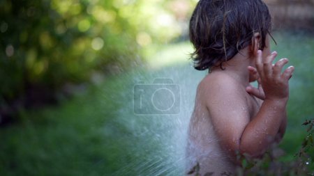 Photo for Water hosing child during summer day outside little boy enjoying vacations running and laughing - Royalty Free Image