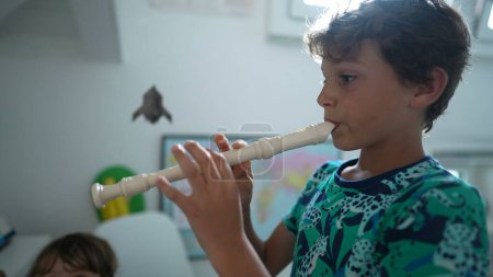 Photo for Kid playing flute young boy plays musical instrument - Royalty Free Image