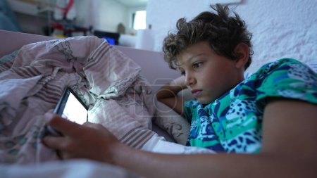 Photo for One addicted child staring at cellphone screen in the morning bed - Royalty Free Image