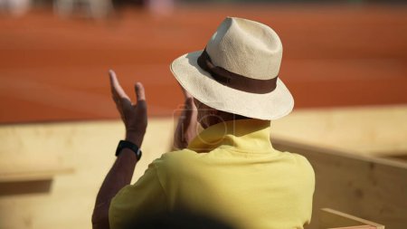 Foto de Espectador viendo partido de tenis aplaudiendo aplaudiendo desde el asiento del estadio usando sombrero de panama - Imagen libre de derechos