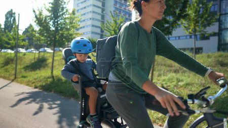 Téléchargez les photos : Mère vélo avec petit garçon assis sur la banquette arrière - en image libre de droit