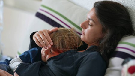 Foto de Madre acostada con su hijo en el sofá descansando - Imagen libre de derechos