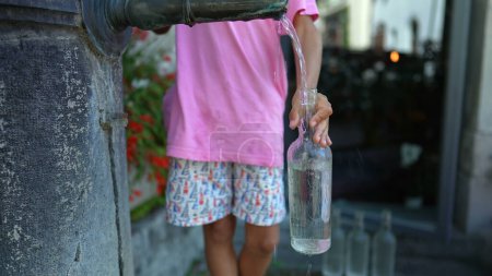 Téléchargez les photos : Bouteille de remplissage pour enfants eau en verre du robinet public - en image libre de droit