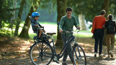Foto de El padre lleva la bicicleta con el niño en el asiento trasero de la bicicleta - Imagen libre de derechos