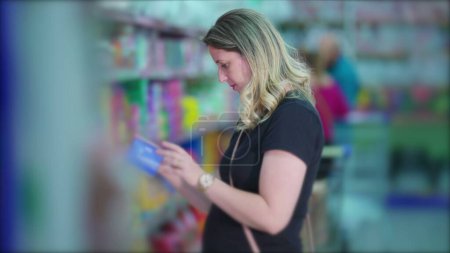 Téléchargez les photos : Choix de l'article par une cliente à partir d'une étagère d'épicerie, représentant le mode de vie des consommateurs - en image libre de droit