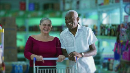 Téléchargez les photos : Heureux divers clients souriant à l'intérieur de l'épicerie d'affaires avec panier - en image libre de droit