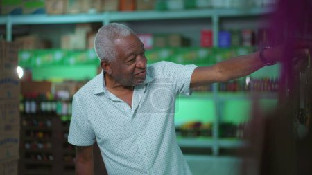 Photo for One black senior shopping for drinks at supermarket. African American elderly person staring at alcoholic aisle, picking product from shelf - Royalty Free Image