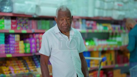 Photo for One black Brazilian senior customer looking for products at grocery store. African American man searching for food items, consumer lifestyle - Royalty Free Image