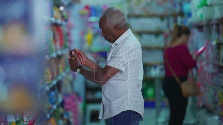 Téléchargez les photos : Clients faisant leurs courses à l'épicerie allée, Candid Afro-Américain à la recherche de produits - en image libre de droit