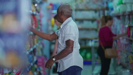 Téléchargez les photos : Clients faisant leurs courses à l'épicerie allée, Candid Afro-Américain à la recherche de produits - en image libre de droit