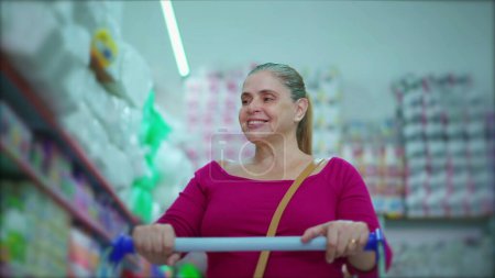 Foto de Mujer de mediana edad que navega por el pasillo del supermercado, navega por los productos del estante, muestra los hábitos de compra del consumidor - Imagen libre de derechos