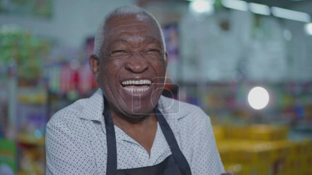 Foto de Feliz afroamericano gerente de supermercado sonriendo y riendo con los brazos cruzados de pie dentro de la tienda de comestibles, concepto de ocupación laboral - Imagen libre de derechos