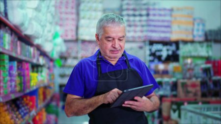 Foto de Happy Male Caucasian Senior Manager de la tienda de comestibles utilizando el dispositivo Tablet para inspeccionar el inventario de productos en el estante del supermercado - Imagen libre de derechos